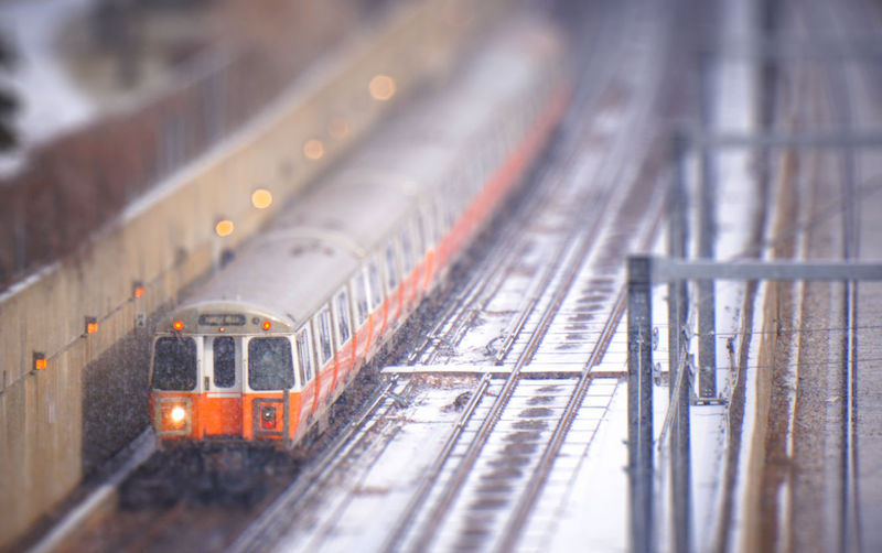 MBTA Orange Line Train moving through winter snow storm. Image illustrates need for climate resilience in transportation system.