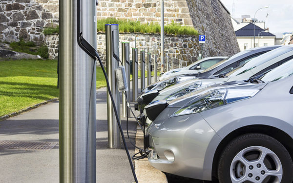 A row of gray electric cars being charged at charging stations.