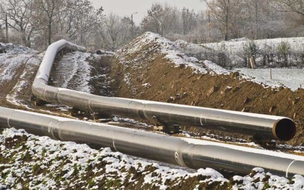 gas pipelines lay on top of dirt covered with snow