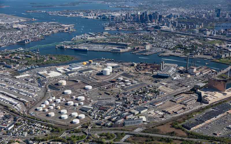 An aerial view of Exxon's tank farm in Everett, MA showing white fuel storage tanks near the waters of Boston Harbor