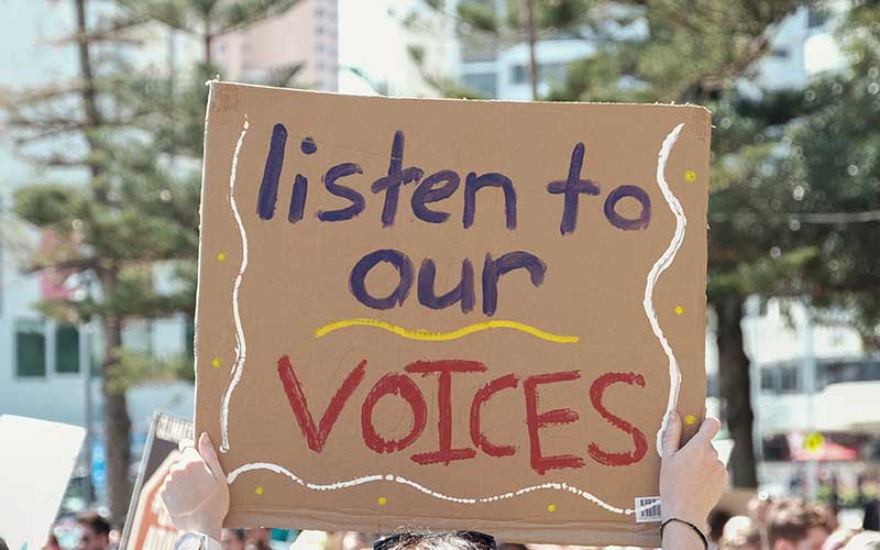 Protest sign reads: Listen to our voices
