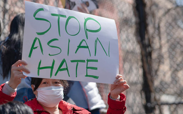 Asian woman holding protest sign that says "Stop Asian Hate"