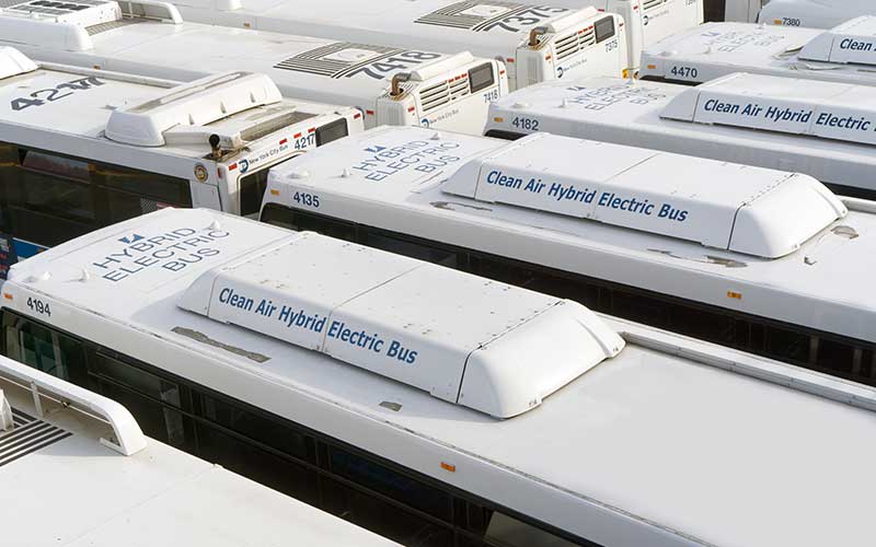 Two diagonal rows of electric busses from an aerial view.