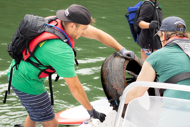Volunteer hands large tire to Melissa Paly, Great Bay Waterkeeper to take it back to shore.