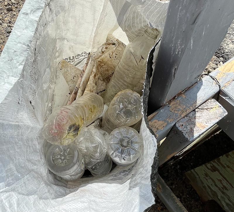 Empty single-use plastic bottles in trash bag.