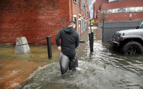 Man wading through flooded water in Boston highlights need for climate resiliency measures