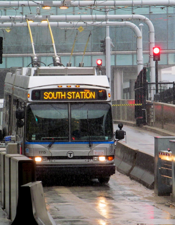 Electric bus heading to South Station through Boston's MBTA Silver Line. Bus goes through light afternoon drizzle.