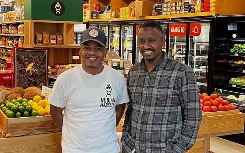 Ismail Samad and Yusuf Yassin stand in their store in front of produce.