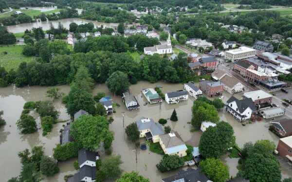 An aerial view of Waterbury, Vermont's flooding during the intense rainstorm of Summer 2023. Houses are submerged up to their doorsteps.