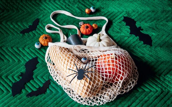 Everything you need for a perfect Green Halloween. A mesh bag with pumpkins, gourds, and candles. DIY bats and spiders made from craft paper. And delicious chocolate eyeballs wrapped in foil.