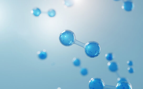 A 3-D rendering of the hydrogen molecule. One is in focus towards the right hand of the image, with a few more in the background not in focus. The image, including the molecules, are varying shades of blue.