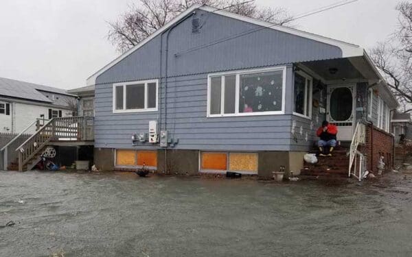 A man sitting on the stoop of a house surrounded by floodwater