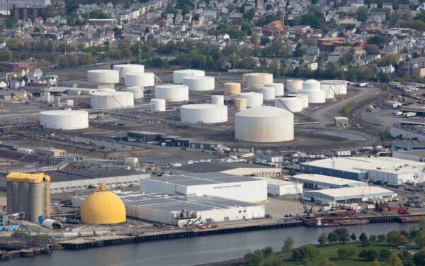 An aerial photo of the Exxon Everett facility, Massachusetts, with a dozen white cylindrical storage tanks and a neighborhood in the background.