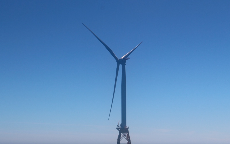 An offshore wind turbine against a blue sky