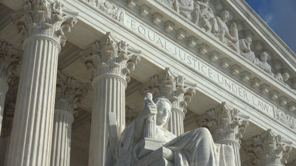 A view of the Supreme Court building in Washington showing statue and columns.