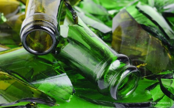 Closeup photo of empty wine bottles in bright green and dark yellow tones. Bottles looked broken and in pieces.