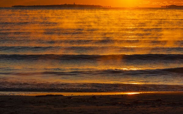 Water laps at a shoreline during sunset