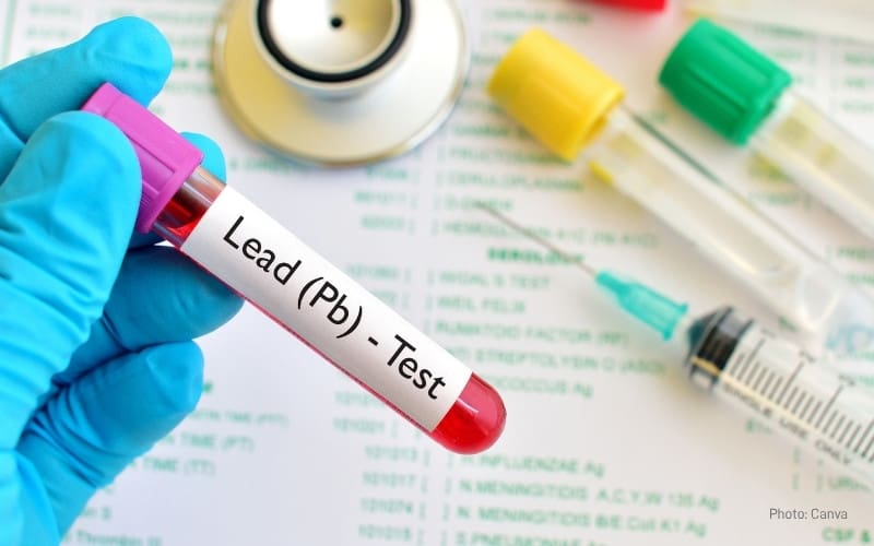Close-up of a gloved hand holding a blood vial labeled 