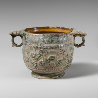 Ancient Roman terracotta pot with decorative relief and a glossy lead-based glaze, showing signs of age and mineral buildup– illustrating early use of lead in everyday household items.