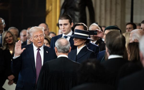 Trump stands with his hand up in the lower left corner of the photo next to Melania and in front of Baron, swearing in as the 47th president.